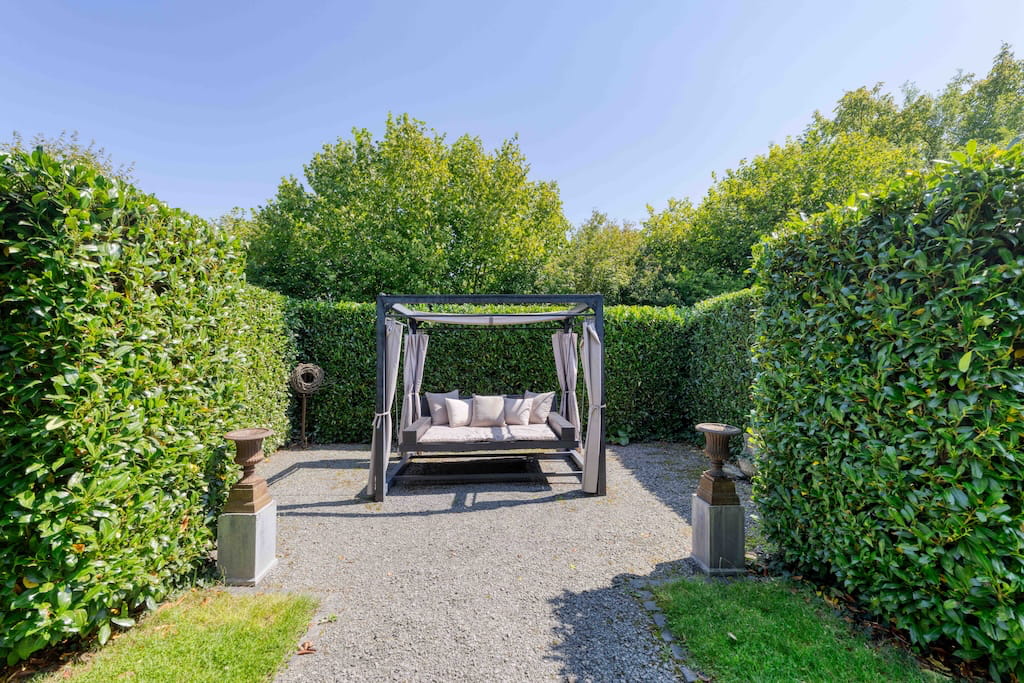 Der Gartenbereich einer Luxusimmobilie in Trier mit gemütlicher Outdoor-Lounge.