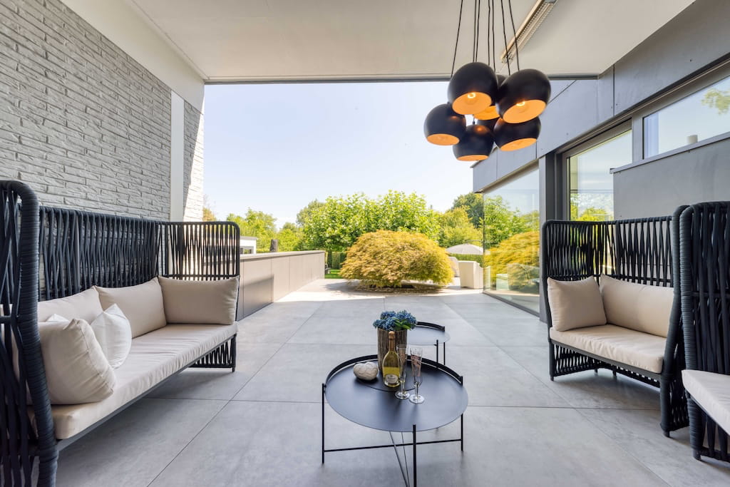 Eine überdachte Terrasse einer Luxusimmobilie mit modernen Loungemöbeln in Trier.