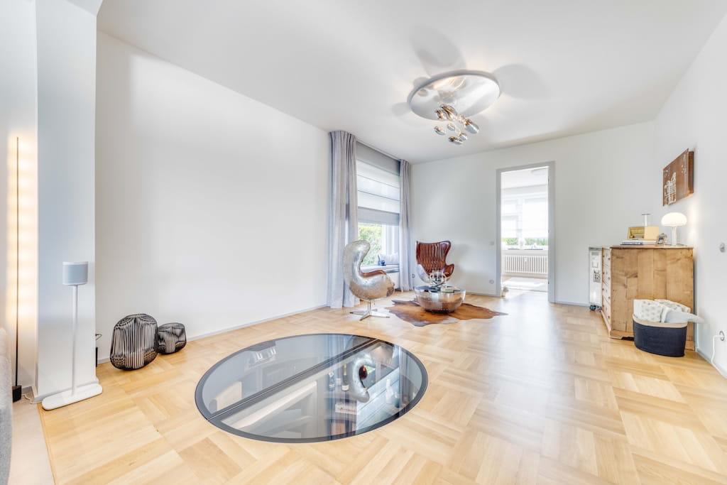 Der Wohnbereich einer Luxusimmobilie in Trier mit Parkettboden und einem Glasbodenelement.